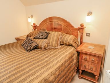 A bedroom with a wooden bed and matching bedside tables at The Red Barn in Longframlington near Alnwick