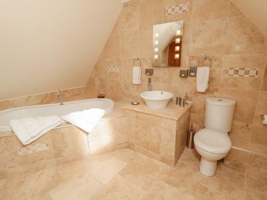 A bathroom with a bathtub sink toilet and towels at The Red Barn in Longframlington near Alnwick