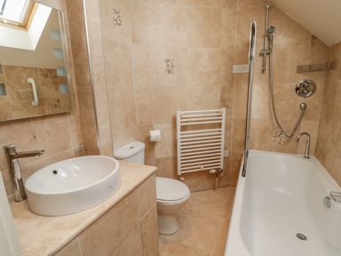 A bathroom with a sink toilet radiator and bathtub with shower at The Red Barn in Longframlington near Alnwick