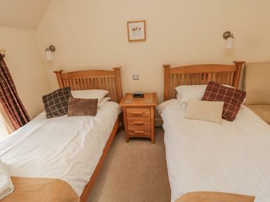 A bedroom with two single beds and a wooden bedside table at The Red Barn in Longframlington near Alnwick