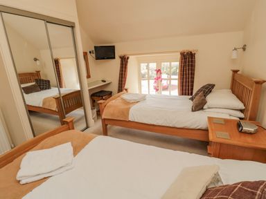 A bedroom with two single beds a bedside table and a wall-mounted TV at The Red Barn in Longframlington near Alnwick