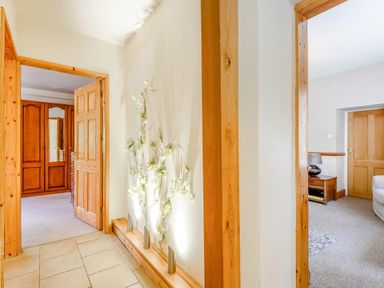 A hallway with wooden door frames and floral wall decor lit by spotlights at Distyll in Llanfwrog near Ruthin