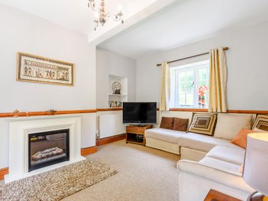 A living room with a sectional sofa a television and a fireplace at Distyll in Llanfwrog near Ruthin