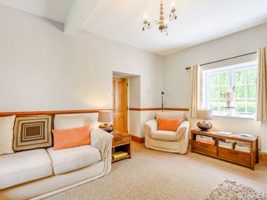 A living room with a sofa an armchair wooden furniture and a window at Distyll in Llanfwrog near Ruthin