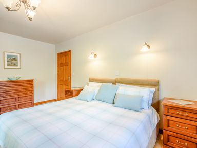 A bedroom with a large bed and wooden furniture at Distyll Llanfwrog near Ruthin