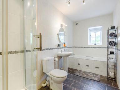 A bathroom with a toilet sink bathtub shower and a window at Distyll in Llanfwrog near Ruthin