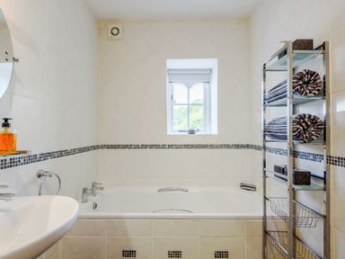 A bathroom with a bathtub sink towels on a metal rack and a window at Distyll in Llanfwrog near Ruthin