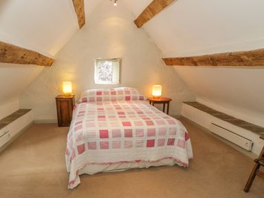 A bedroom with a double bed and two bedside tables with lamps at Pembridge Cottage in Welsh Newton