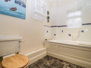 A bathroom with a bathtub and toilet with wooden seat at Colly Cottage in Dottery