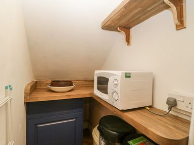 A small kitchen nook with a microwave on a wooden countertop and bowls on the side at Colly Cottage in Dottery
