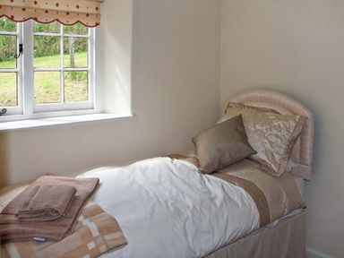A single bed with pillows and folded towels near a window in a bedroom at Tuckermarsh Quay River Cottage 2 Bere Alston near Tavistock