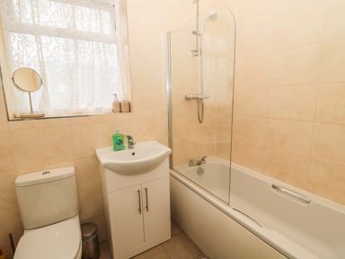A bathroom with a toilet a sink with cabinet a bathtub and a shower at Coquet Cottage in Amble