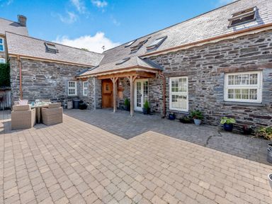 A stone exterior building with outdoor seating on a paved courtyard at Ysgubor Uchaf in Brongest near Newcastle Emlyn