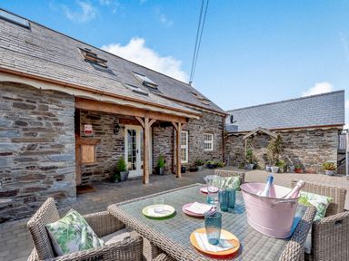 An outdoor patio with stone walls several skylights and a table set with plates glasses and a bucket of bottles at Ysgubor Uchaf in Brongest near Newcastle Emlyn