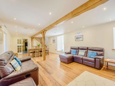 A living room with leather sofas wooden floors and a dining table with chairs at Ysgubor Uchaf in Brongest near Newcastle Emlyn