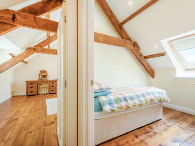 A bedroom with exposed wooden beams a bed and a dressing table with stool at Ysgubor Uchaf Brongest near Newcastle Emlyn
