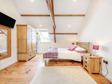A bedroom with wooden bed frame wooden wardrobe bedside table and a wall mirror at Ysgubor Uchaf in Brongest near Newcastle Emlyn