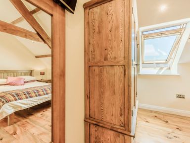 A bedroom with a bed and wooden wardrobe near a window at Ysgubor Uchaf in Brongest near Newcastle Emlyn