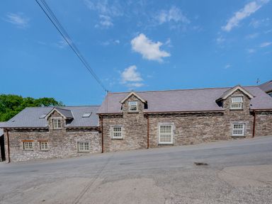 A stone building with small windows on a sloped road at Ysgubor Uchaf in Brongest near Newcastle Emlyn