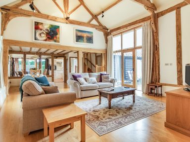 A living room with two sofas a wooden coffee table and large windows at Ducksfoot Barn Bush Green near Pulham Market