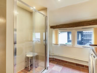 A utility room with a shower enclosure and a stool next to washing machines at Ducksfoot Barn Bush Green near Pulham Market
