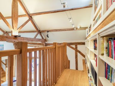 An upstairs hallway with wooden railing and bookshelf along the wall at Ducksfoot Barn Bush Green near Pulham Market