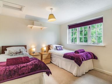 A bedroom with two single beds a window and bedside tables at Ducksfoot Barn Bush Green near Pulham Market