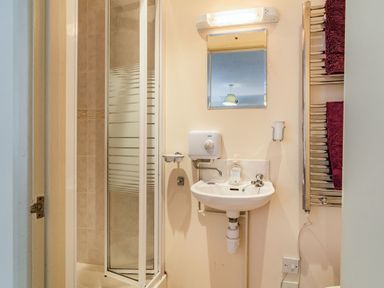 A bathroom with a shower enclosure sink mirror and towel rail with towels at Ducksfoot Barn Bush Green near Pulham Market