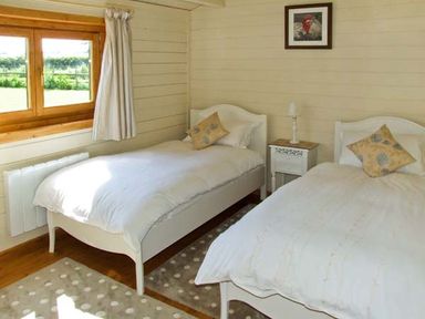 A bedroom with two single beds a window and a small bedside table at Cropvale Lodge in Cropthorne near Pershore