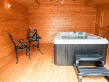 A wooden room with a hot tub black plastic steps and a metal table with two chairs at Cropvale Lodge Cropthorne near Pershore