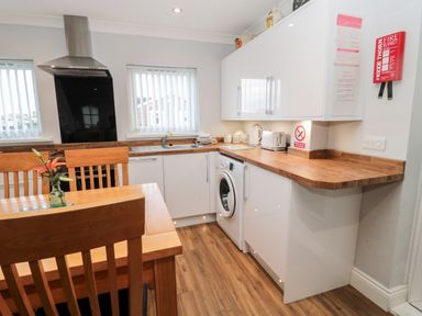 A kitchen with wooden floor white cabinets wooden countertop and dining table with chairs at Cheviot View in Beadnell