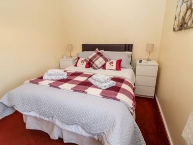 A bedroom with a bed with patterned and plain pillows two bedside tables with lamps and folded towels on the bed at Cheviot View in Beadnell