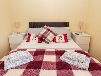 A bedroom with a bed with pillows and folded towels on a checkered blanket at Cheviot View in Beadnell