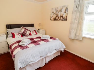 A bedroom with a double bed pillows bedside tables and a window at Cheviot View in Beadnell