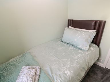 A single bed with a brown headboard a pillow bedcover and folded towels on it at Cheviot View in Beadnell