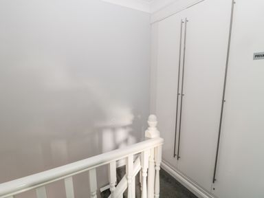 A white staircase railing next to white double doors with long handles in a hallway at Cheviot View in Beadnell