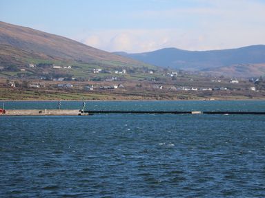 A body of water with a dock and houses on hills in the background at Kates Cottage in Knightstown Valentia Island County Kerry