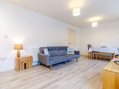 A living room with a blue sofa and wooden table with a lamp at Sunrise The Bay near Filey