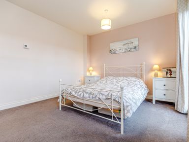 A bedroom with a bed with patterned bedding two bedside tables with lamps and a painting on the wall at Sunrise The Bay near Filey