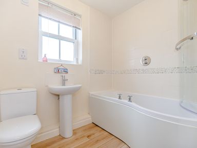 A bathroom with a toilet sink and bathtub with a tiled wall at Sunrise The Bay near Filey
