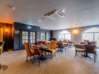 A dining area with multiple tables and chairs and large windows at Sunrise The Bay near Filey