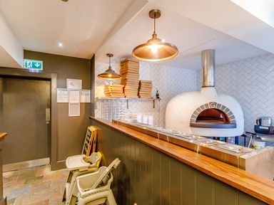 A pizza oven with pizza boxes and food containers on a counter in a restaurant kitchen