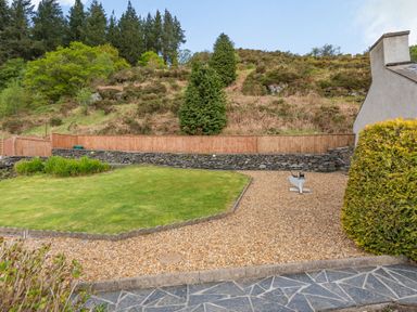 A garden with grass lawn gravel path wooden fence stone wall and hill in the background at Henrhiw Bach in Penmachno