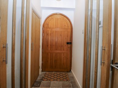 A hallway with wooden doors and a door mat at Eglwys St Cynfil Penrhos near Pwllheli
