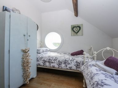 A bedroom with two beds and a wardrobe at Eglwys St Cynfil Penrhos near Pwllheli
