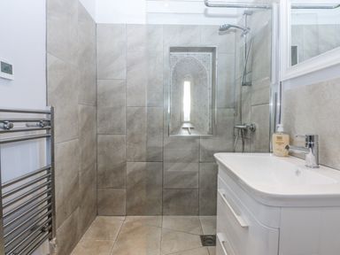 A bathroom with a shower and washbasin at Eglwys St Cynfil Penrhos near Pwllheli