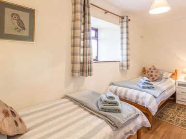 A bedroom with two single beds with striped bedding and towels on each bed at Ridge Cottage in Whitridge