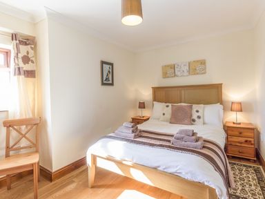 A bedroom with a wooden bed and bedside tables with lamps at Ridge Cottage in Whitridge