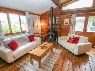 A living room with two white sofas and a wood burning stove at Timbertwig Lodge in Lamphey near Pembroke