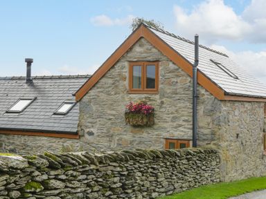 Stone house with slate roof and flower box above window near mossy stone wall at Pendre Uchaf Melin-y-Wig near Ruthin